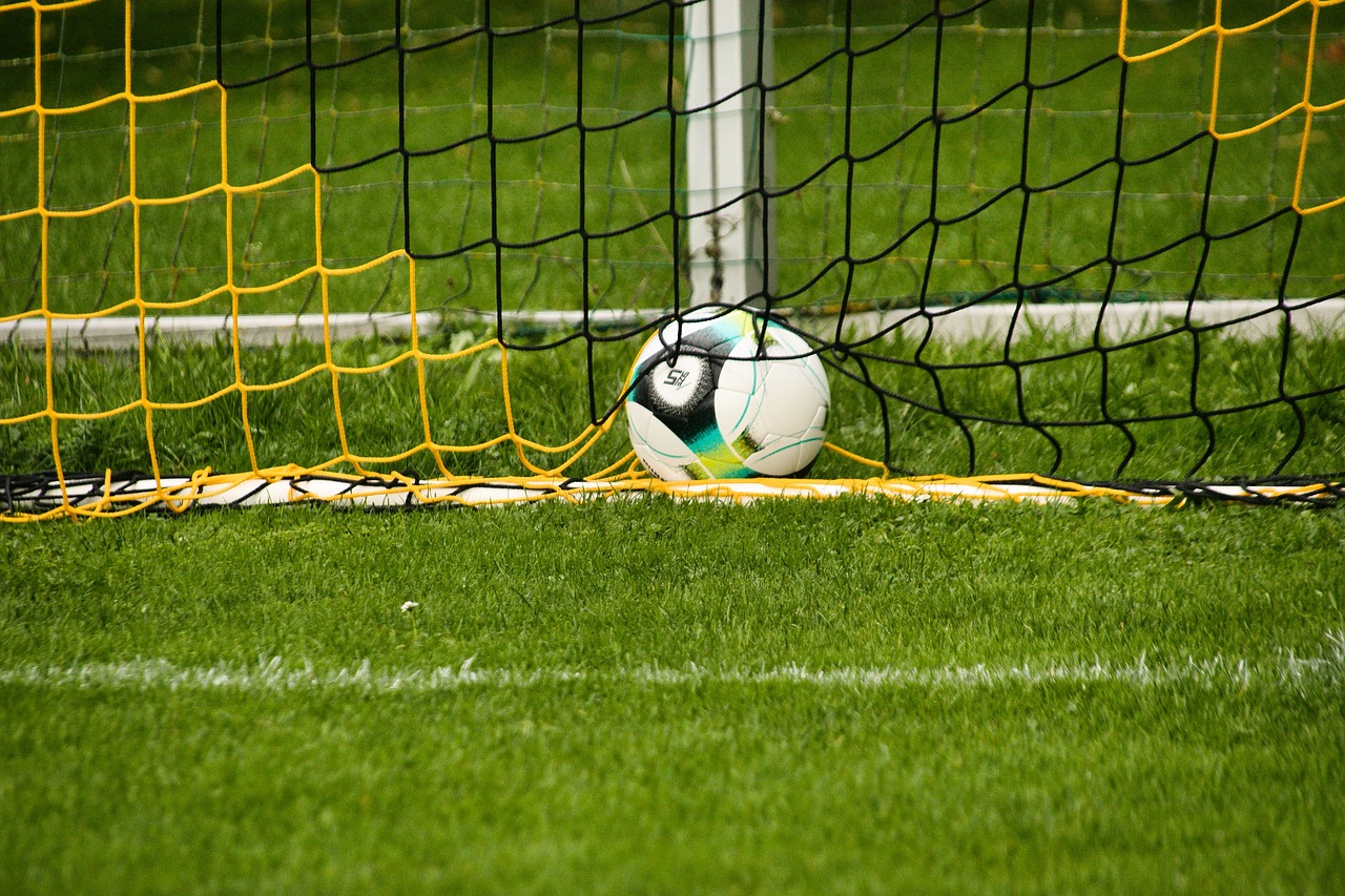 Fußball im Netz eines gelb-schwarzen Tores auf grünem Rasen, ruhend mit ruhiger Umgebung.