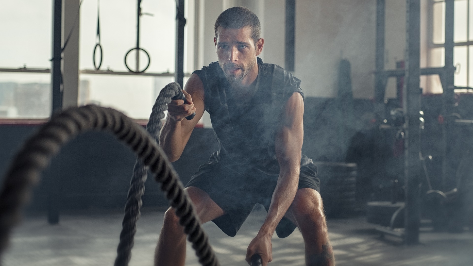 Young man exercising using battle rope